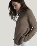 Woman wearing a brown sweater against a gray background