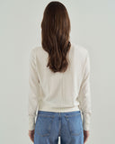 Person wearing a white long-sleeve shirt and blue jeans against a plain background