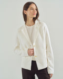 Woman wearing a white blazer over a white shirt on a light gray background