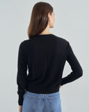 Person wearing a black sweater and blue jeans on a plain background