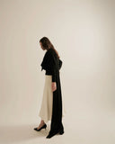 Woman wearing a black dress with a white skirt against a beige background